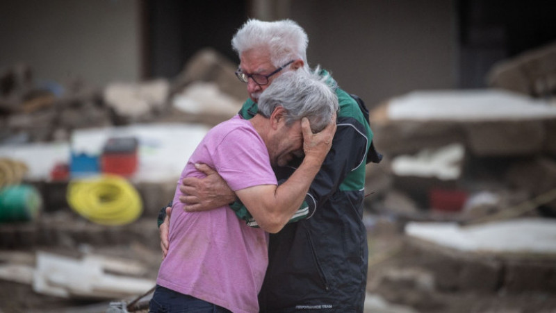 Doi frați plâng în fața casei părinților lor din landul Renania-Palatinat, distrusă de inundații. Sursa foto: Boris Roessler/dpa
