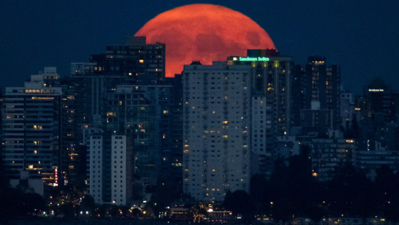 Luna plină de deasupra orașului Vancouver, Canada, are nuanțe portocalii, din cauza inendiilor de begetație. Foto: Profimedia