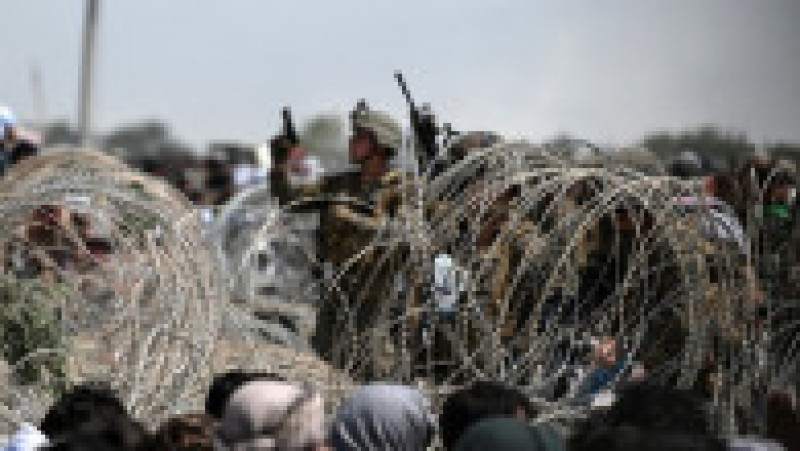 Un soldat american aflat în spatele unui gard de sârmă ghimpată trage focuri de avertisment în aer lângă aeroportul din Kabul Foto: Profimedia | Poza 17 din 40