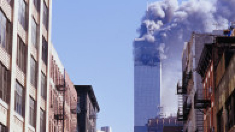 Un bărbat privește de la fereastră spre primul turn WTC lovit de avionul deturnat de teroriști. Foto: Profimedia Images | Poza 1 din 19