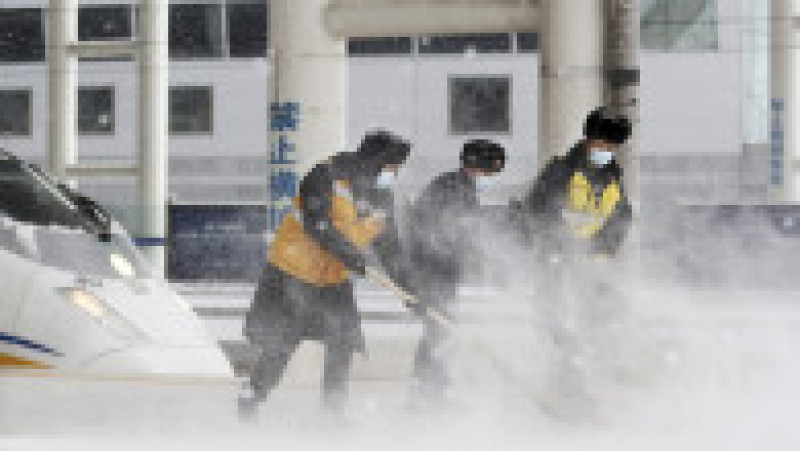Mai mulți muncitori curăță zăpada de pe asfalt în nord-estul Chinei. Sursă foto: Profimedia Images | Poza 10 din 11