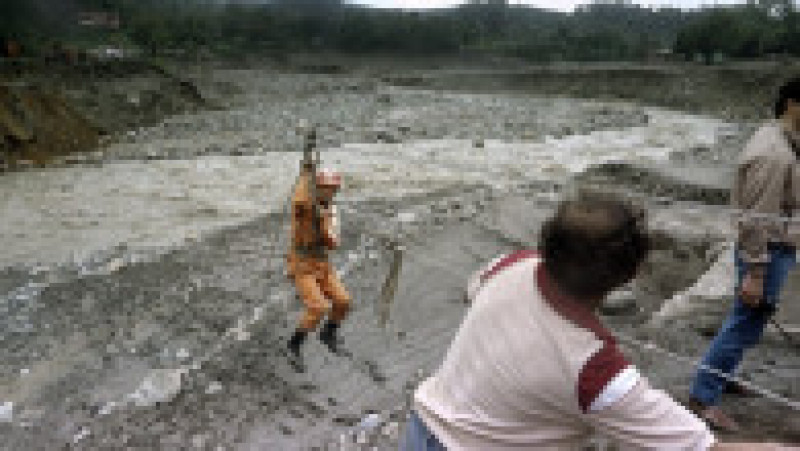 Un membru al echipelor de salvare trece râul Chinchina din Armero. Sursa foto: Profimedia Images | Poza 11 din 29