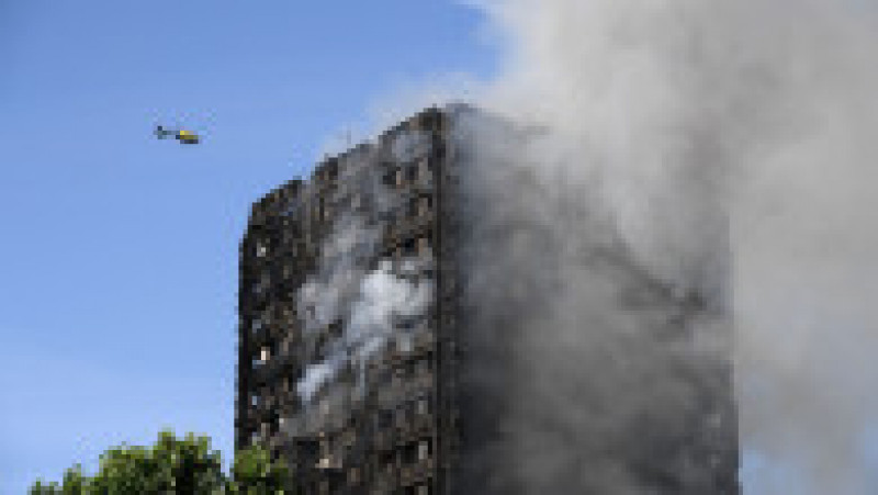 LONDON, ENGLAND - JUNE 14: A heicopter circles as smoke rises from the building after a huge fire engulfed the 24 story Grenfell Tower in Latimer Road, West London in the early hours of this morning on June 14, 2017 in London, England. The Mayor of London, Sadiq Khan, has declared the fire a major incident as more than 200 firefighters are still tackling the blaze while at least 50 people are receiving hospital treatment. (Photo by Carl Court/Getty Images) | Poza 6 din 13