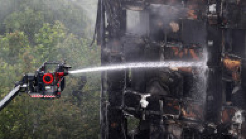 LONDON, ENGLAND - JUNE 15: A hose continues to douse the fire at Grenfell Tower on June 15, 2017 in London, England. At least 17 people have been confirmed dead and dozens missing, after the 24 storey residential Grenfell Tower block in Latimer Road was engulfed in flames in the early hours of June 14. The number of fatalities are expected to rise. (Photo by Dan Kitwood/Getty Images) | Poza 11 din 13