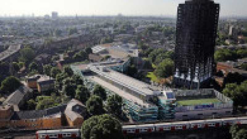 LONDON, ENGLAND - JUNE 15: A train drives past Grenfall tower, as it continues to smoulder on June 15, 2017 in London, England. At least twelve people have been confirmed dead and dozens missing after the 24 storey residential Grenfell Tower block in Latimer Road was engulfed in flames in the early hours of June 14. The number of fatalities are expected to rise. (Photo by Dan Kitwood/Getty Images) | Poza 1 din 13
