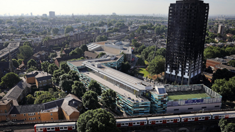 LONDON, ENGLAND - JUNE 15: A train drives past Grenfall tower, as it continues to smoulder on June 15, 2017 in London, England. At least twelve people have been confirmed dead and dozens missing after the 24 storey residential Grenfell Tower block in Latimer Road was engulfed in flames in the early hours of June 14. The number of fatalities are expected to rise. (Photo by Dan Kitwood/Getty Images)