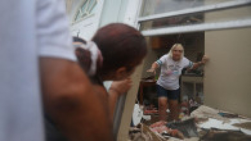 ROCKPORT, TX - AUGUST 26: Donna Raney makes her way out of the wreckage of her home as Daisy Graham tells her she will help her out of the window after Hurricane Harvey destroyed the apartment on August 26, 2017 in Rockport, Texas. Donna was hiding in the shower after the roof blew off and the walls of her home caved in by the winds of Hurricane Harvey. Harvey made landfall shortly after 11 p.m. Friday, just north of Port Aransas as a Category 4 storm and is being reported as the strongest hurricane to hit the United States since Wilma in 2005. Forecasts call for as much as 30 inches of rain to fall by next Wednesday. (Photo by Joe Raedle/Getty Images) | Poza 9 din 15