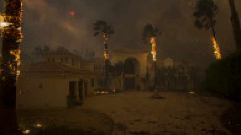 MALIBU, CA - NOVEMBER 09: Embers falls from burning palms and the sun is obscured by smoke as flames close in on a house at the Woolsey Fire on November 9, 2018 in Malibu, California. About 75,000 homes have been evacuated in Los Angeles and Ventura counties due to two fires in the region. (Photo by David McNew/Getty Images) | Poza 7 din 10