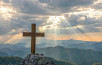 Silhouettes of crucifix symbol on top mountain with bright sunbeam on the colorful sky background