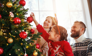 happy family mother, father and child daughter decorate Christmas tree