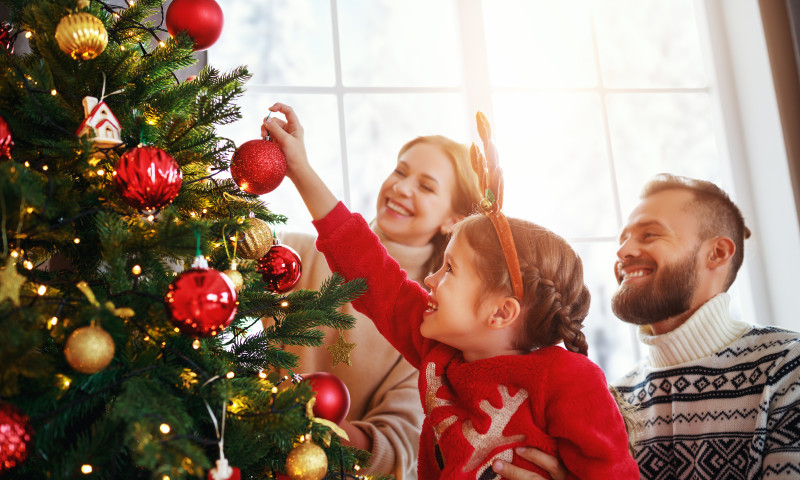happy family mother, father and child daughter decorate Christmas tree