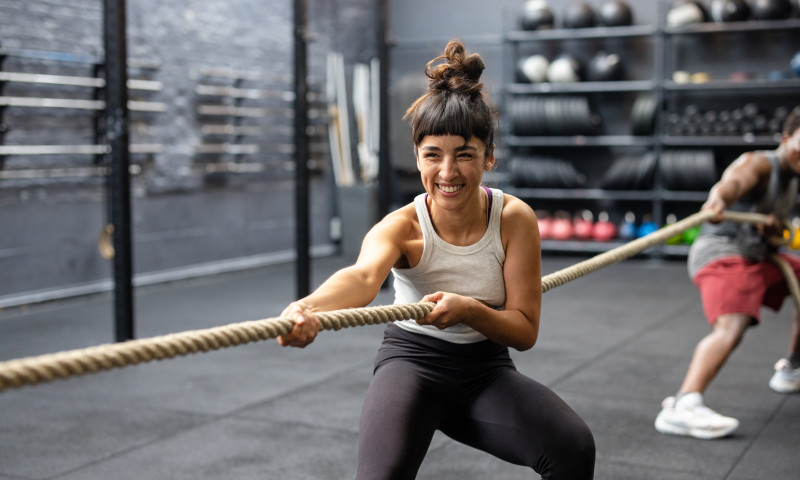 Group of fitness people playing tug of war at a cross training gym