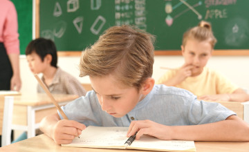 Happy caucasian boy looking at camera while studying math at school. Pedagogy.